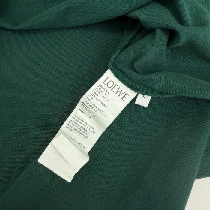 Capo Loewe in tessuto verde elegante, con etichetta visibile e stile raffinato.