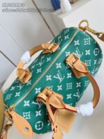 Borsa elegante verde con motivi iconici in bianco e dettagli in pelle marrone.