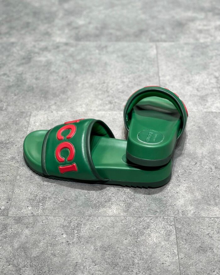 Sandali Gucci verdi con logo rosso, stile moderno, comfort e design di alta qualità.