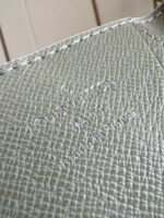 Superba pelle verde con logo embossato, dettagli raffinati e riflessi di alta qualità.