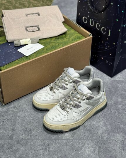 Sneakers grigie di lusso con packaging Gucci, stile moderno e dettagli eleganti.