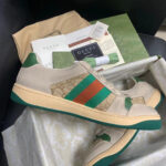 Sneakers Gucci beige con strisce colorate, dettagli di lusso e packaging elegante.
