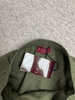 Maglione Gucci verde oliva con etichetta di lusso e dettaglio elasticizzato al collo.