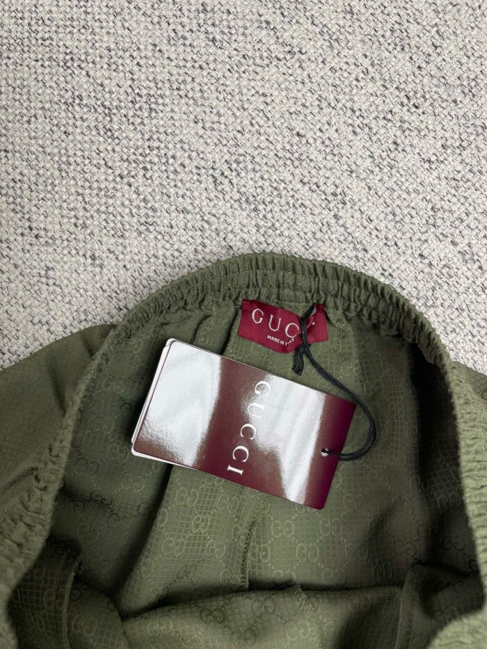 Maglione Gucci verde oliva con etichetta di lusso e dettaglio elasticizzato al collo.