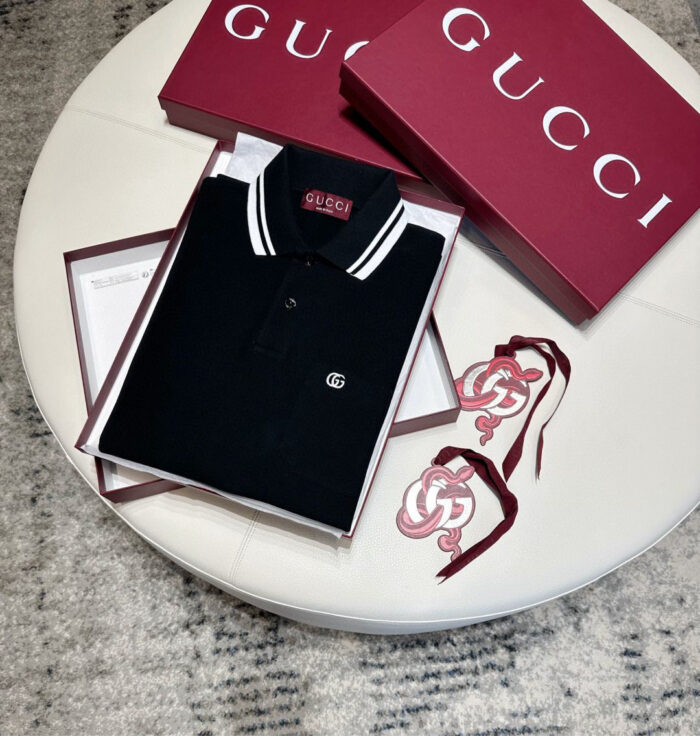Polo Gucci nera con confezioni rosse e dettagli eleganti su tavolo raffinato.