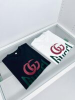 Magliette Gucci nere e bianche in vetrina di lusso con logo iconico e design elegante.