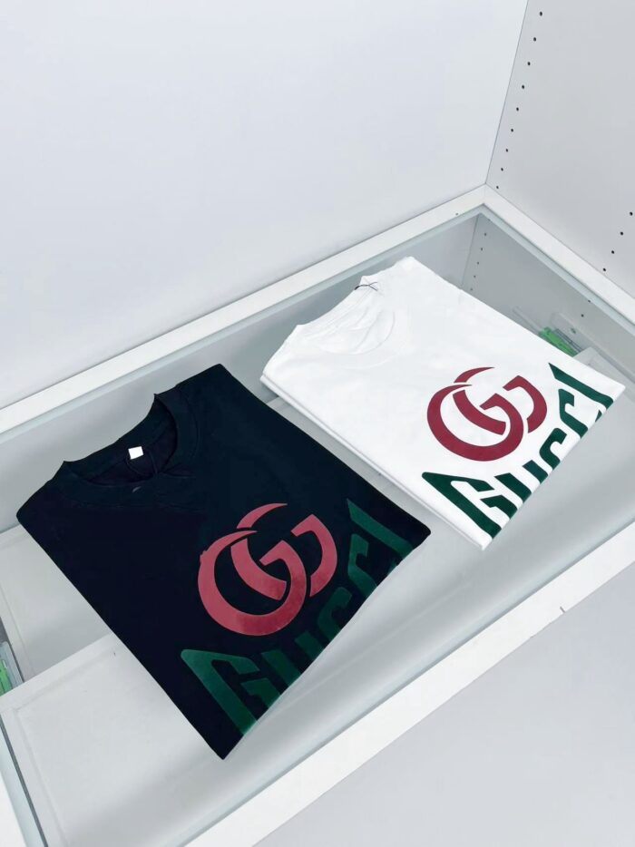 Magliette Gucci nere e bianche in vetrina di lusso con logo iconico e design elegante.