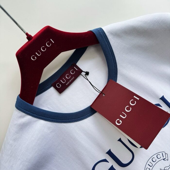 Maglietta Gucci bianca con bordo navy, hanger di lusso e etichetta autentica.