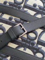 Maniglia in pelle nera con fibbia elegante su borsa moderna con motivo geometrico beige e nero.