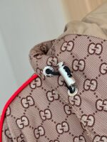 Giacca di lusso con logo interlock, dettaglio rosso e chiusura metallica elegante.