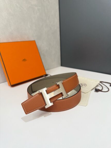 Cintura di lusso in pelle con fibbia a H in argento, packaging elegante, stile sofisticato.