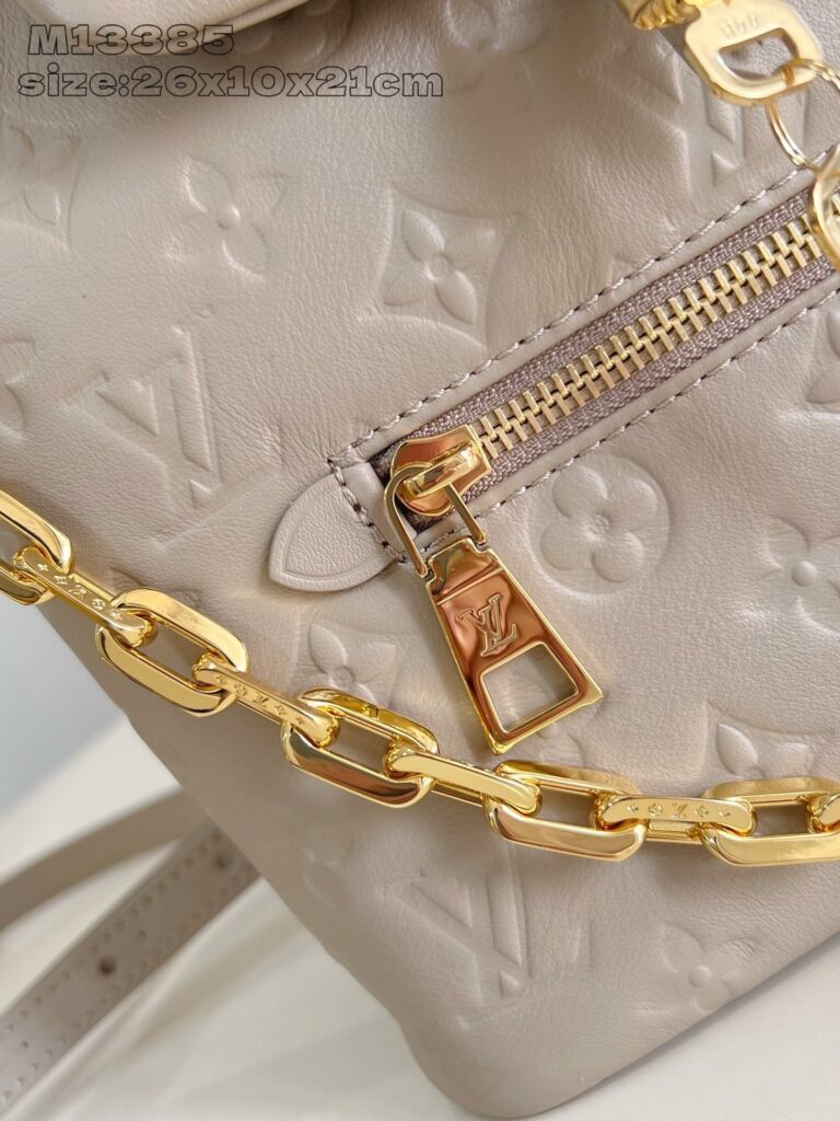 Borsa di lusso in pelle beige con dettagli dorati e logo embossato, elegante e versatile.