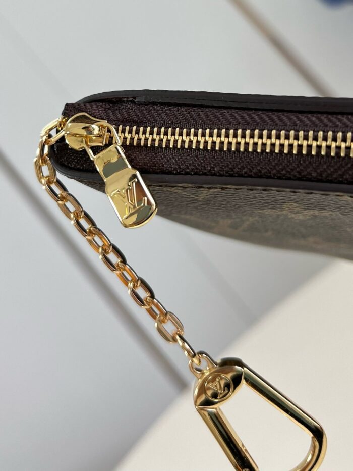 Portafoglio di lusso con zip e catena in oro, dettagli eleganti e materiali di alta qualità.