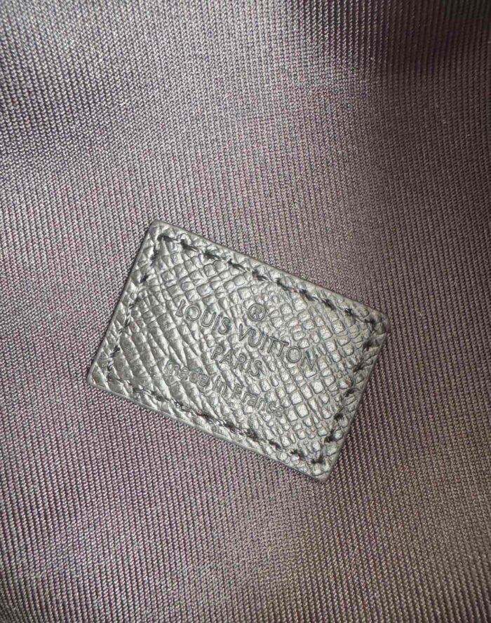 Etichetta Louis Vuitton in pelle di lusso, dettaglio rugoso e cuciture precise.