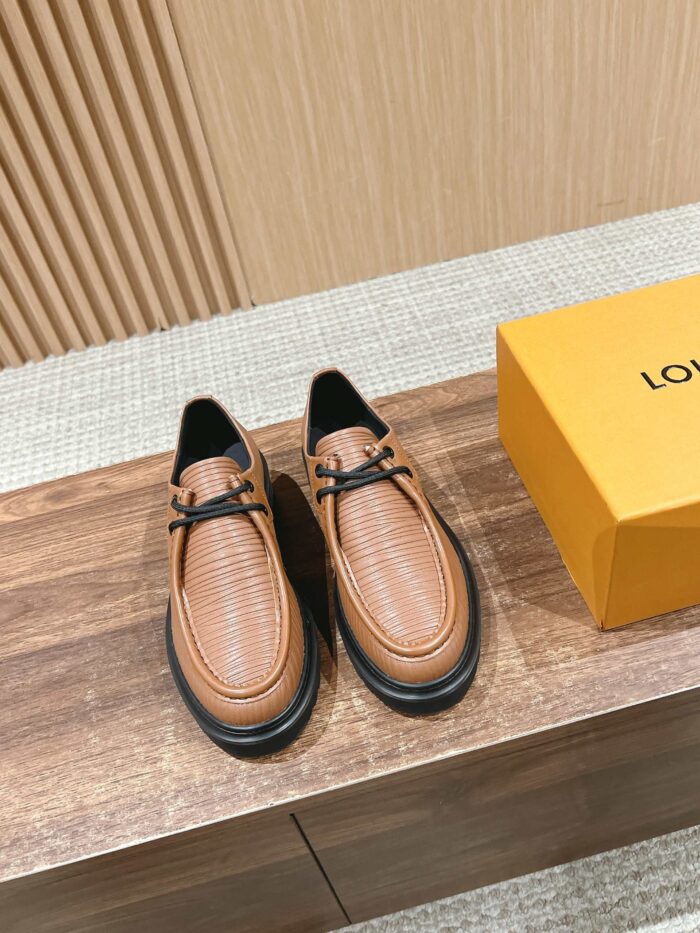 Scarpe in pelle cognac di lusso con scatola arancione, stile elegante e artigianale.