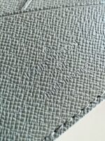 Texture elegante in grigio con logo Louis Vuitton inciso, dettagli raffinati e cuciture di alta qualità.
