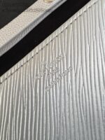 Dettaglio di pelle argentata con logo embossato, texture elegante e finiture di alta qualità.
