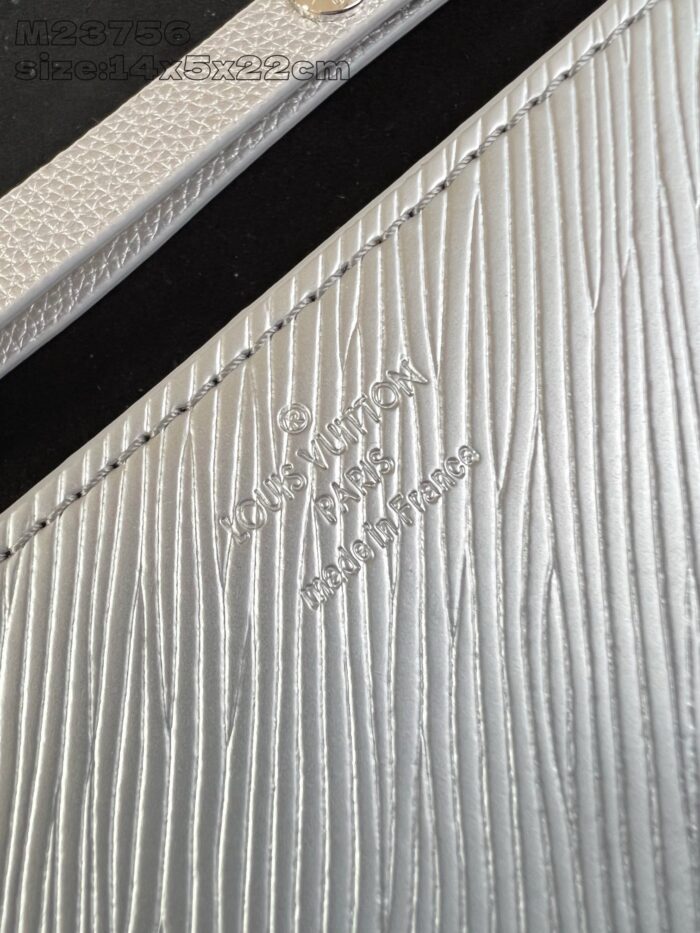 Dettaglio di pelle argentata con logo embossato, texture elegante e finiture di alta qualità.