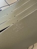 Texture di pelle sintetica verde con linee perforate e logo discreto, elegante e di alta qualità.