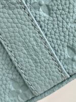 Dettaglio di pelle color menta con cuciture rinforzate e superficie tessellata elegante.