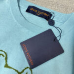 Maglione Louis Vuitton blu pastello con ricamo verde e etichetta di lusso.