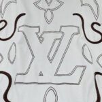 Tessuto ricamato Louis Vuitton con logo iconico e motivi eleganti, stile di lusso sofisticato.