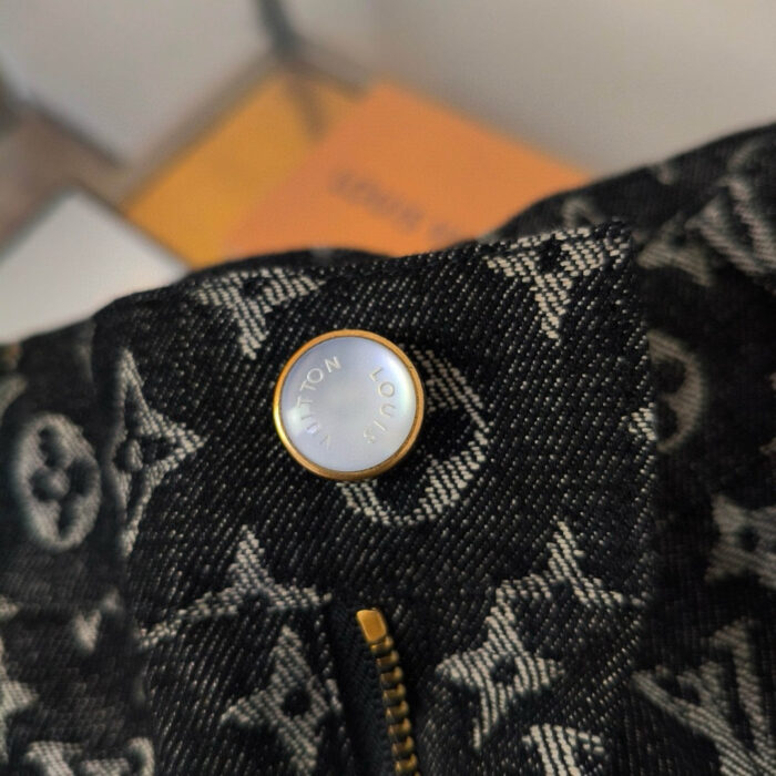 Dettaglio di giacca Louis Vuitton con bottoni doro e monogramma in denim scuro.