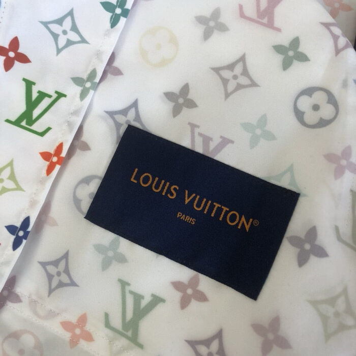 Tessuto Louis Vuitton con motivi colorati e etichetta in oro, simbolo di eleganza e lusso.
