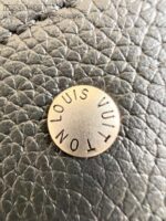 Emblema in metallo Louis Vuitton su pelle di alta qualità per accessori di lusso.
