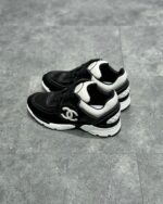 Sneaker di lusso neri e bianchi con design chunky, dettagli in suede e pelle, logo distintivo.