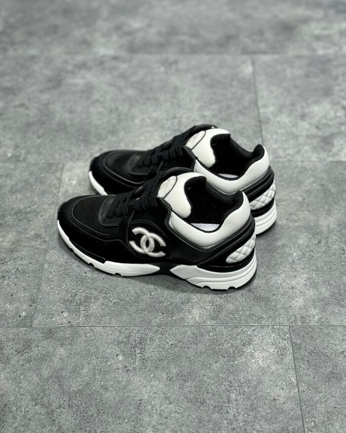 Sneaker di lusso neri e bianchi con design chunky, dettagli in suede e pelle, logo distintivo.