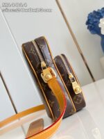 Borsa monogramma elegante con dettagli oro e tracolla arancione vibrante.