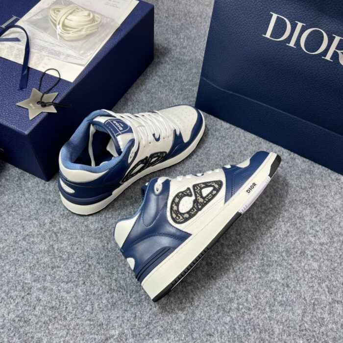 Sneakers di lusso navy e bianco con logo distintivo e scatola Dior elegante.