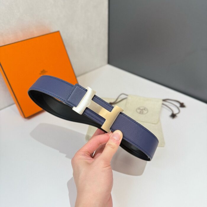 Cintura in pelle navy con fibbia elegante, confezione di lusso e design moderno.