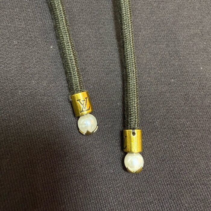 Cordi con aglet dorato e perla, dettagli elegante su abbigliamento casual e di lusso.