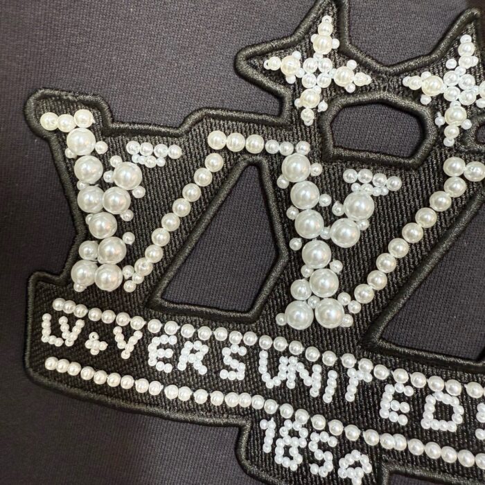 Logo LV in paillettes e perle, eleganza e lusso con dettagli stellari.