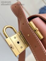 Borsa elegante in pelle marrone con chiusura oro, dettaglio di stile e alta qualità.