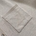 Tasca beige con logo embossato e dettagli a costina, stile minimalista e raffinato.