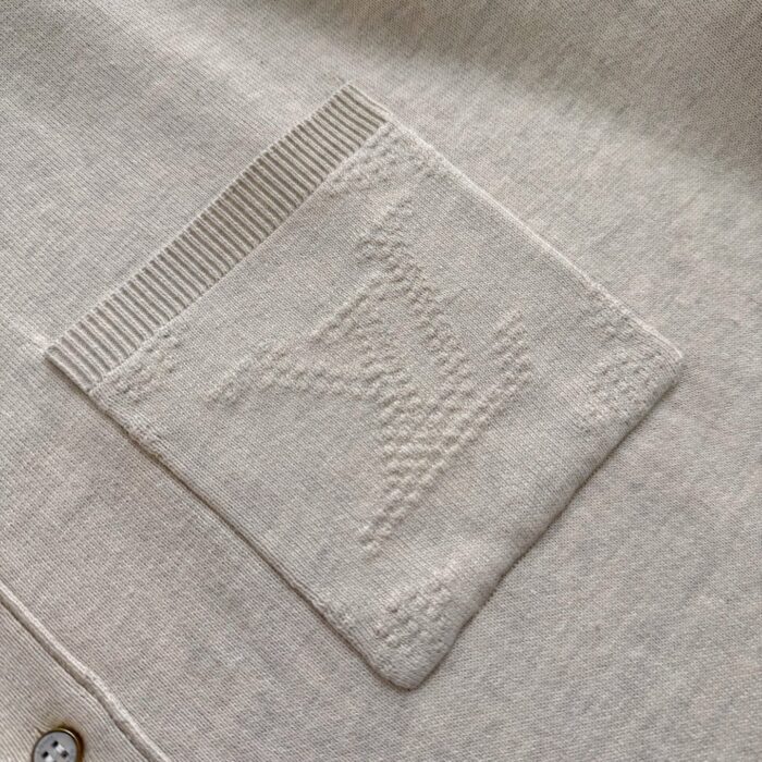 Tasca beige con logo embossato e dettagli a costina, stile minimalista e raffinato.