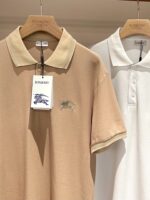 Polo di lusso beige e bianca su hanger in display elegante, stile e qualità raffinata.