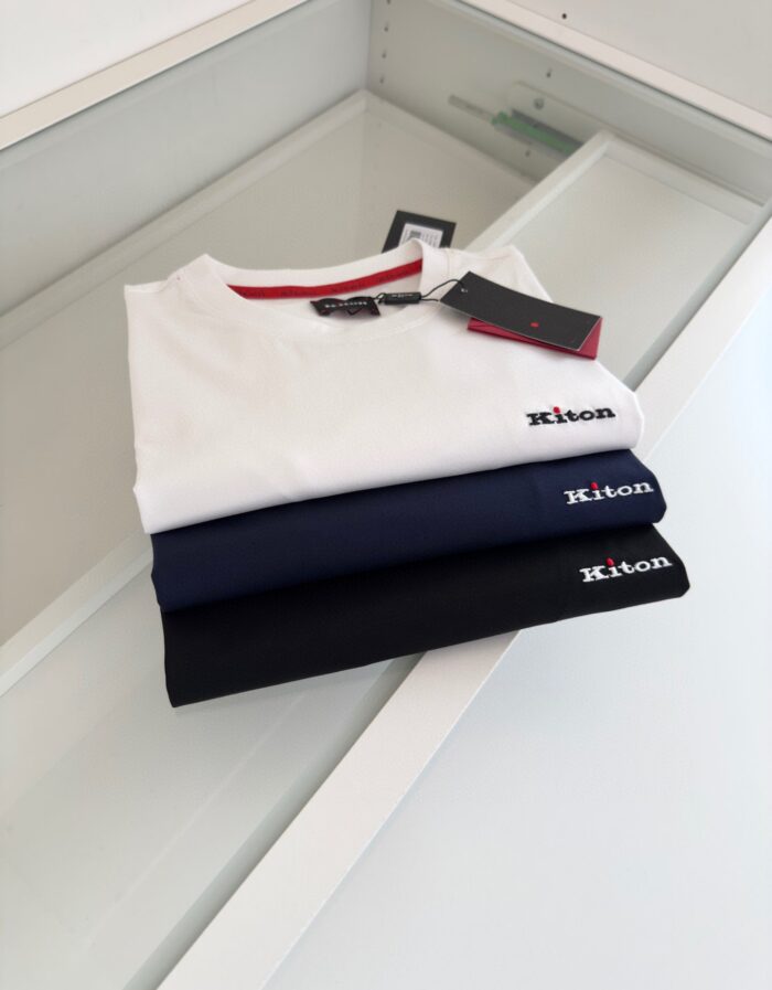 Magliette Kiton di lusso in bianco e navy su display elegante con riflessi raffinati.