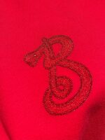 Emblema elegante ricamato su tessuto rosso intenso, stile logo animale e lettera B.