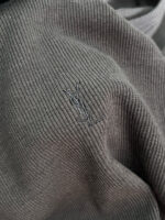 Maglia in maglia grigia con logo minimalista ricamato, eleganza sobria e dettagli di alta qualità.