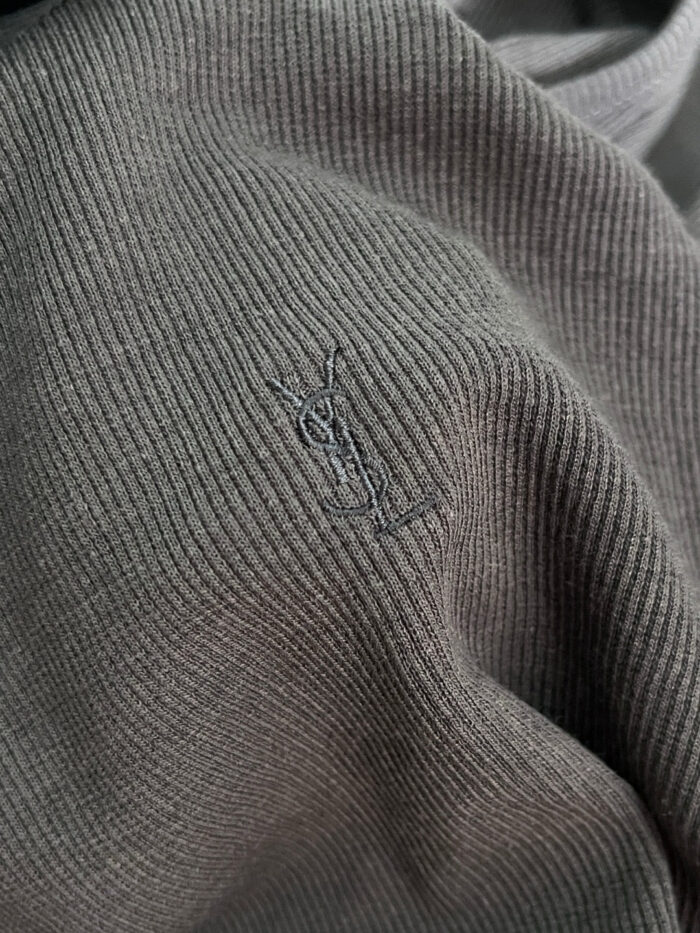 Maglia in maglia grigia con logo minimalista ricamato, eleganza sobria e dettagli di alta qualità.