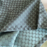 Tessuto di seta di lusso con monogramma elegante e lucentezza raffinata.