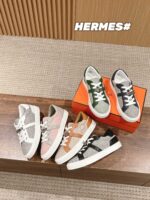 Sneaker Hermès di lusso in vari colori su base in legno con scatola arancione elegante.