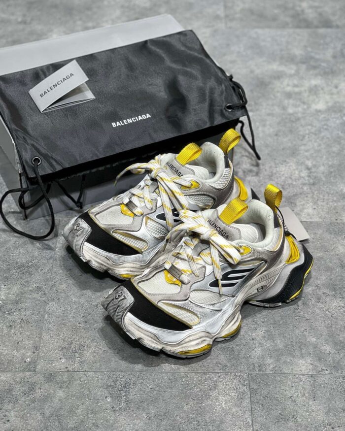 Sneakers Balenciaga bianche con dettagli gialli e neri, stile moderno e luxury.
