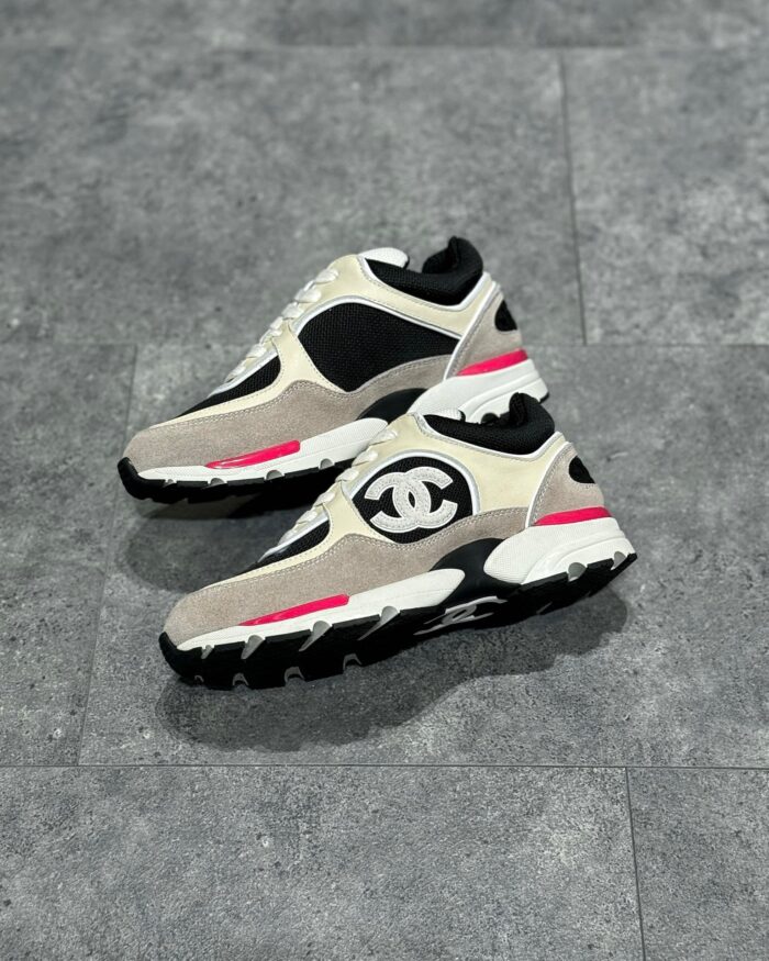 Sneakers di lusso beige, nero e rosa con design sportivo, logo distintivo e dettagli moderni.