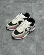 Sneakers di lusso nero, bianco e grigio con dettagli rossi, design moderno e suola chunky.