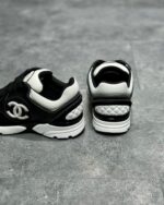 Sneakers di lusso nero e bianco con dettagli quilt, logo iconico e suola antiscivolo elegante.